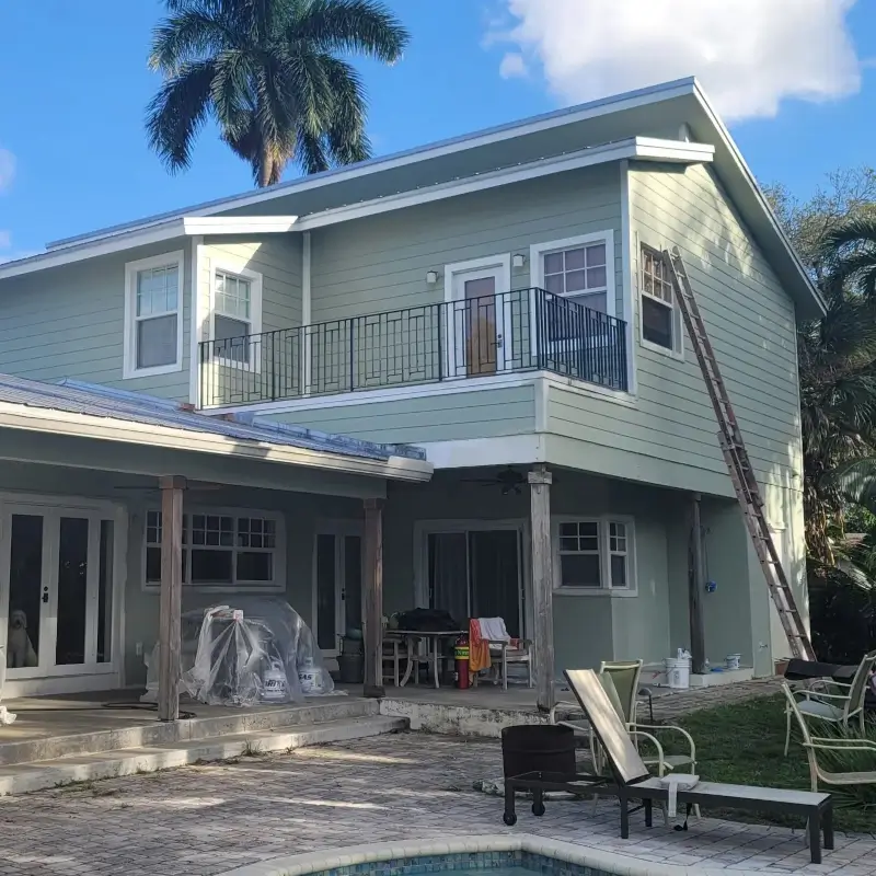 Sage green and white exterior paint colors on a two-story Miami home with a pool