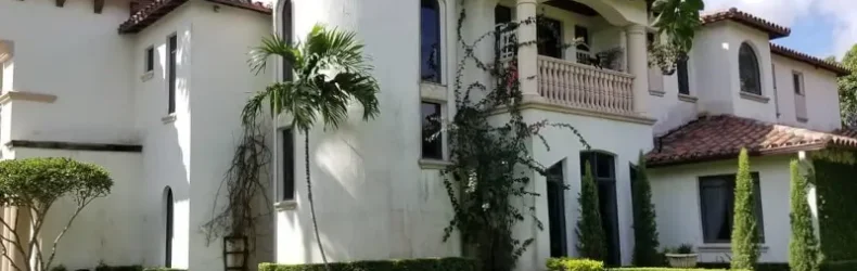 White Mediterranean Revival stucco home with terracotta barrel-tile roof showing classic Miami paint colors