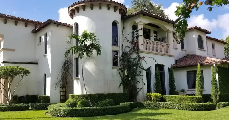 White Mediterranean Revival stucco home with terracotta barrel-tile roof showing classic Miami paint colors